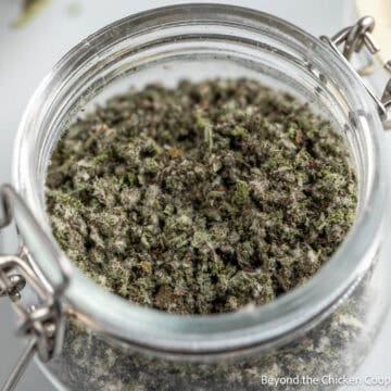 A jar filled with dried ground sage leaves.