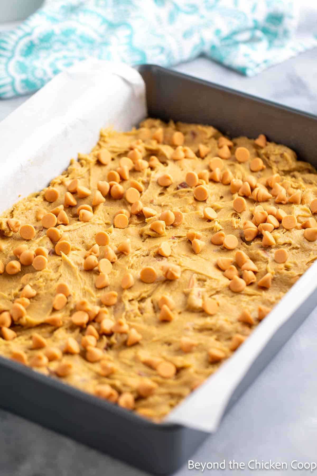 Dough topped with butterscotch chips in a baking pan. 