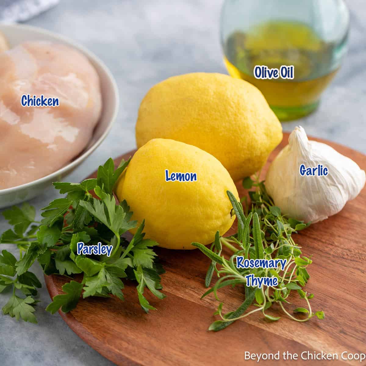 Lemons, herbs, garlic and chicken on a wooden board. 