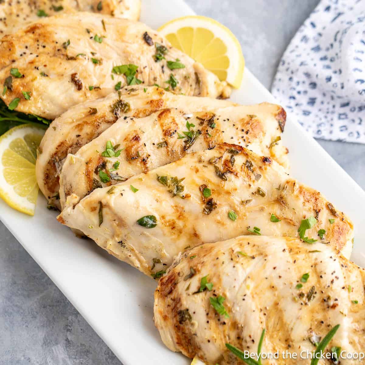 Lemon Herb Chicken with lemon slices on a white plate.