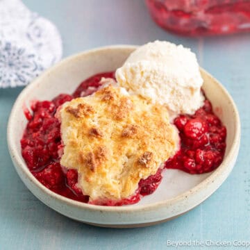 Raspberry Cobbler in a bowl topped with a scoop of ice cream.