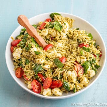 Pesto Orzo Salad with tomatoes, spinach and mozzarella in a large bowl.